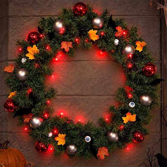 Halloween wreath with autumn leaves, red lights, bats, eyeball ornaments and silver decorations